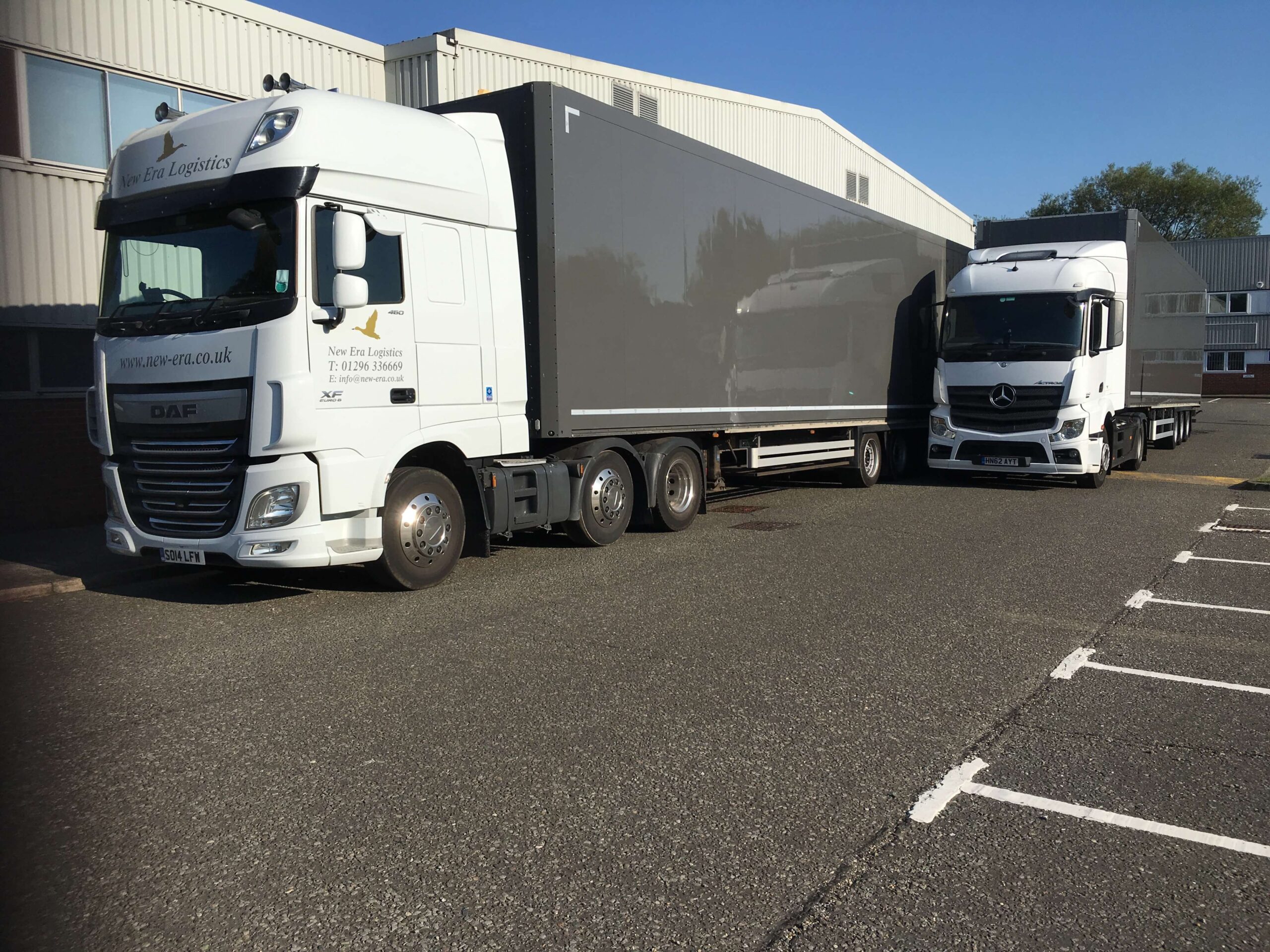 Two grey event trucks outside a warehouse